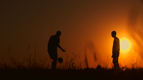 Zwei-Jungen-Spielen-Bei-Sonnenuntergang-Fußball.-Silhouette-Von-Kindern,-Die-Bei-Sonnenuntergang-Mit-Einem-Ball-Spielen.-Das-Konzept-Einer-Glücklichen-Familie.